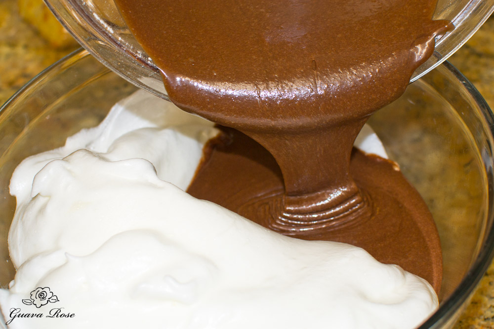 Pouring choc cake batter into bowl with whipped egg whites