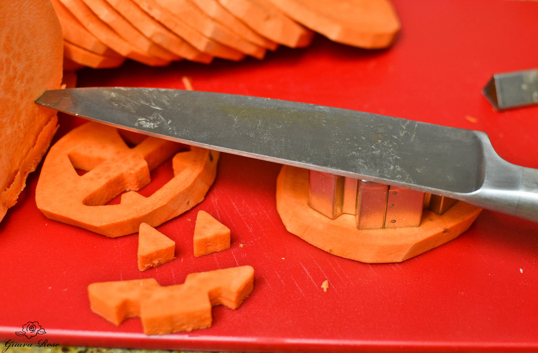 Pressing jack-o-lantern face cutters into sweet potato slices