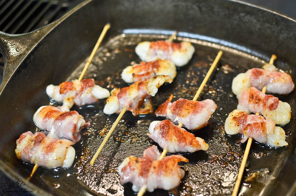Bacon wrapped mochi frying in cast iron pan